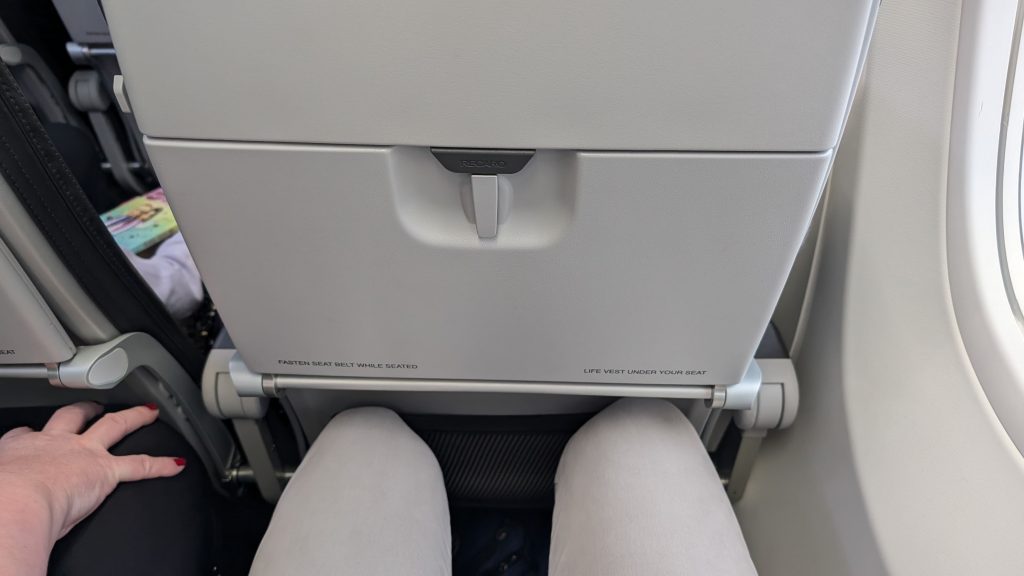 Sitzplatz im Flugzeug mit Sitzabstand und grauer Sitzlehne vorne