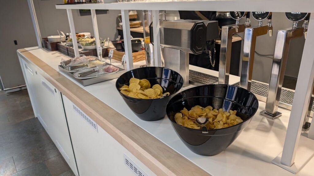 Auslage mit Kartoffelchips in schwarzen Schalen neben den Zapfhähnen des Loungebuffets