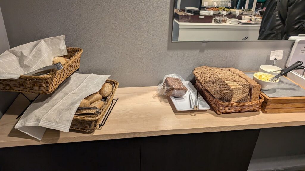 Holztresen mit Brotkörben voller Weizenbrötchen und aufgereihtem schwedischen Knäckebrot samt Butter