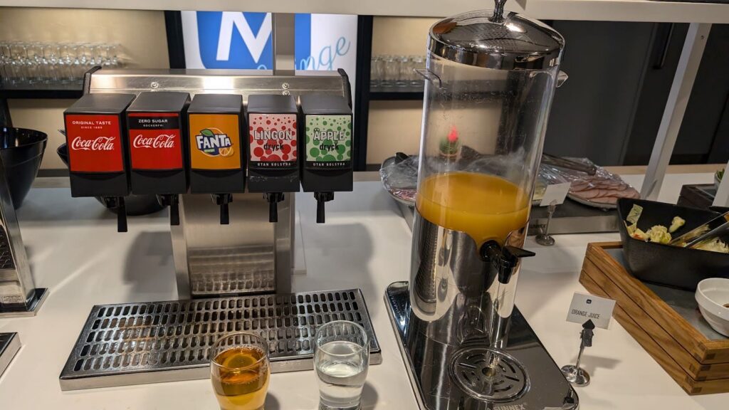 Schankanlage für Erfrischungsgetränke neben einem zylindrischen Spender mit Orangensaft